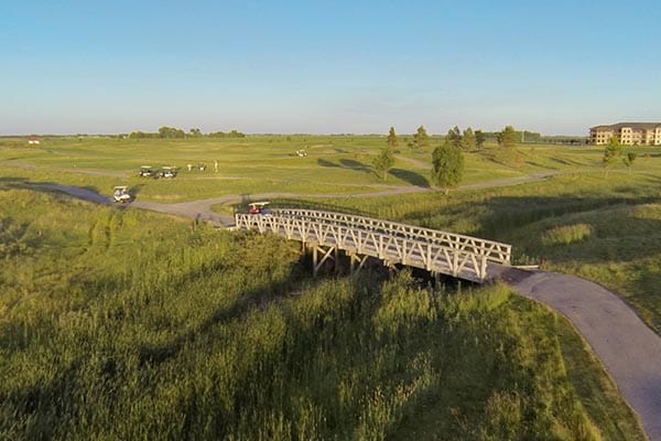Aerial view of King's Walk Golf Course with the signature bridge and the clubhouse beyond