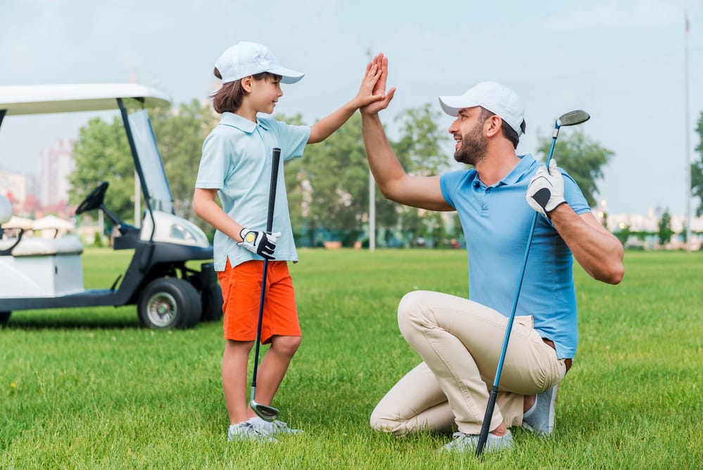 A young golfer high-fives on the course at a King's Walk youth golf camp